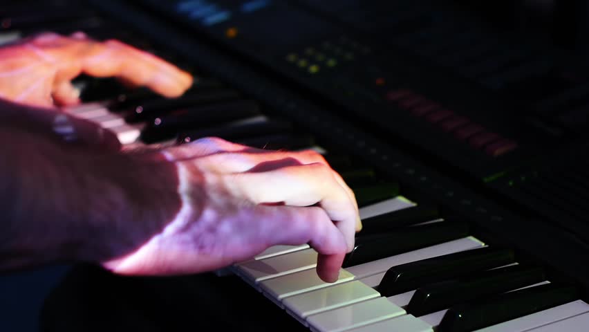 hands of a man playing a synthesizer in the light
