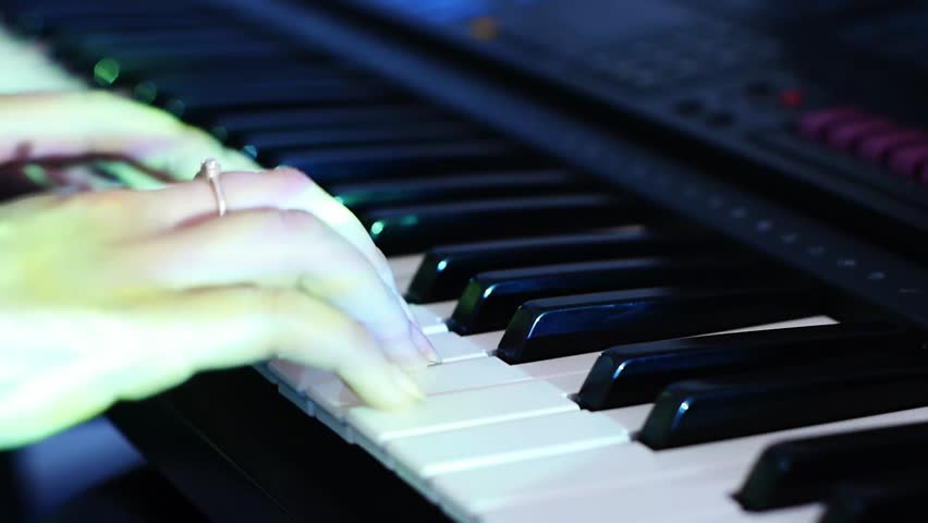 hands of a woman playing a piano