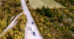 Autumn color road, Cinema 4k aerial rising view following a car on 970 the tenontie road full of different colors, near tenojoki river, on a cloudy day, in Lapland, Finland