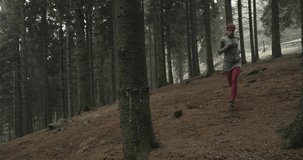 Athlete girl running through forest woods.Following front.Real people woman runner sport training in autumn or winter in wild mountain outdoors nature, bad foggy weather.4k 60p slow motion video