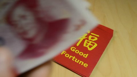 The red envelope or hong bao used for giving money during the Chinese New Year 2018, the dog's year. Envelope with the chinese words meaning Good fortune, the dog's silhouette on it, and yuan bills.