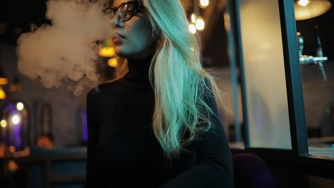 Woman vaping hookah in night club