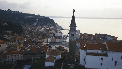 A fly by a church over the main square at a beautiful  mediterranean town Piran Slovenia.  Drone shot 4K