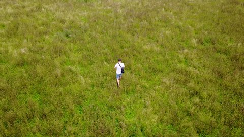 4k aerial drone footage follow above man walking through long meadow grass