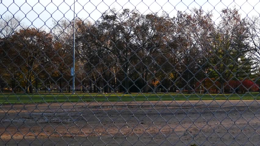 Chain link fence surrounding baseball field at park.