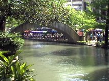Video of the San Antonio Texas Riverwalk. Tourist barge under foot bridge. Tourist and passengers. Walk, business, umbrellas and bridge. Vacation. 