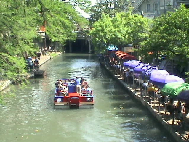 Video of the San Antonio Texas Riverwalk. Vacation Tourist barge near restaurant area. Tourist and passengers. Walk, business, umbrellas and bridge. Vacation.