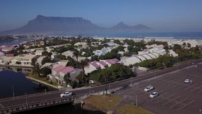 4K high quality aerial video scenic sunny morning view of historical lighthouse area and lagoon, Table Mountain at the background near beach at sea shore in Milnerton, Cape Town, South Africa