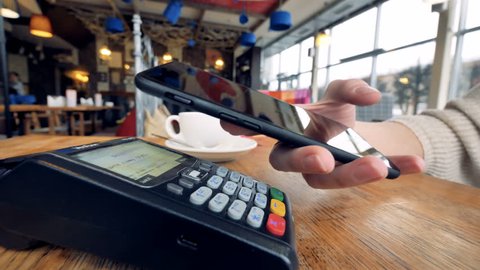 Smartphone payment. Female hand pay using nfc system and contactless card.