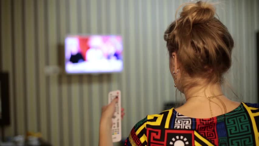 Woman on the bed with TV remote control.