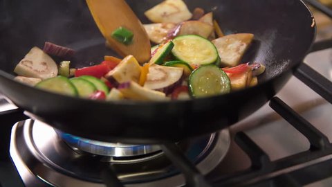Cooking healthy and organic vegetables in a wok. Cook is turning wok with special movements so vegetables flip.