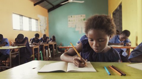 4k close view of pupils in classroom of African children writing English in school notebooks.