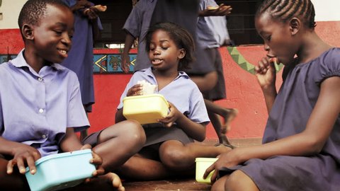 4k of African school children eating packed lunch at playtime break.