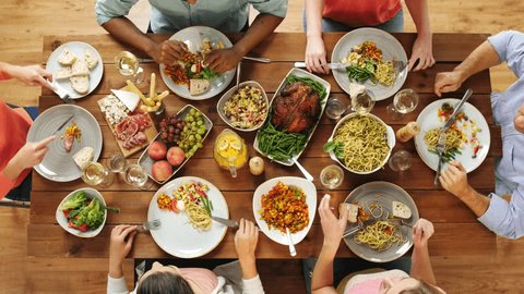 eating and leisure concept - group of people having dinner at table with food Video de stock