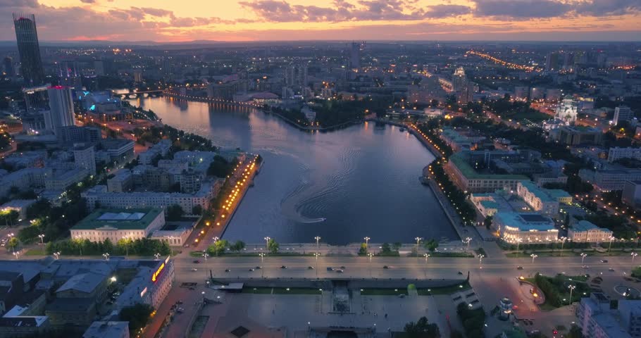Aerial view of Yekaterinburg city center featuring Iset river bank and Lenina Street traffic at sunset, flying backward. Ural region, Russia. 4K UHD.