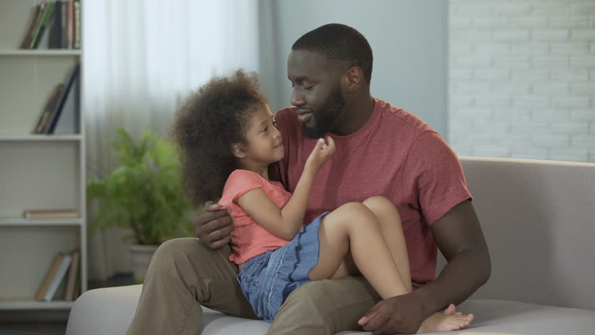 Dad holding his little daughter on lap gently hugging her, conscious parent...