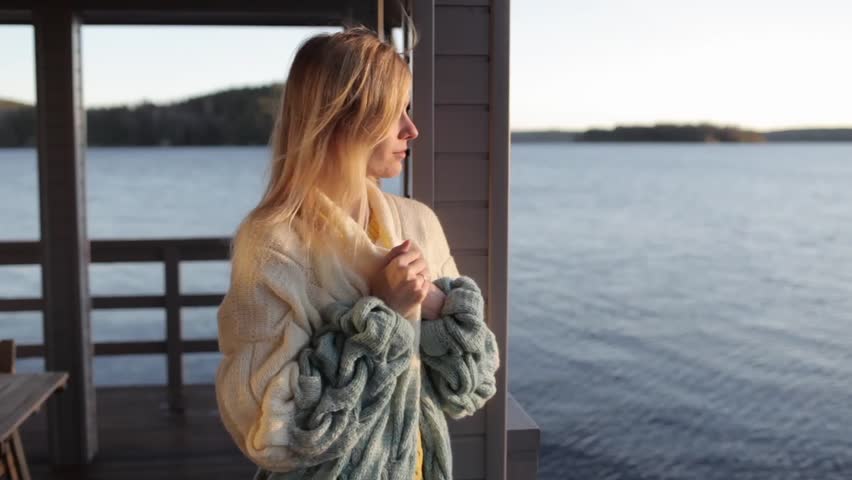 beautiful woman is standing on pier near water