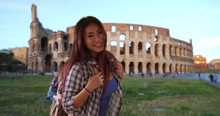 Cute Japanese woman excited to be in Rome. Portrait of tourist smiling and jumping near Coliseum. 4k