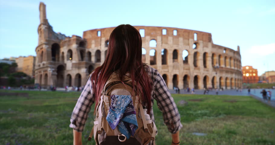 Japanese woman excited to see Coliseum. Cute Asian female backpacking in Italy jumping and smiling. 4k