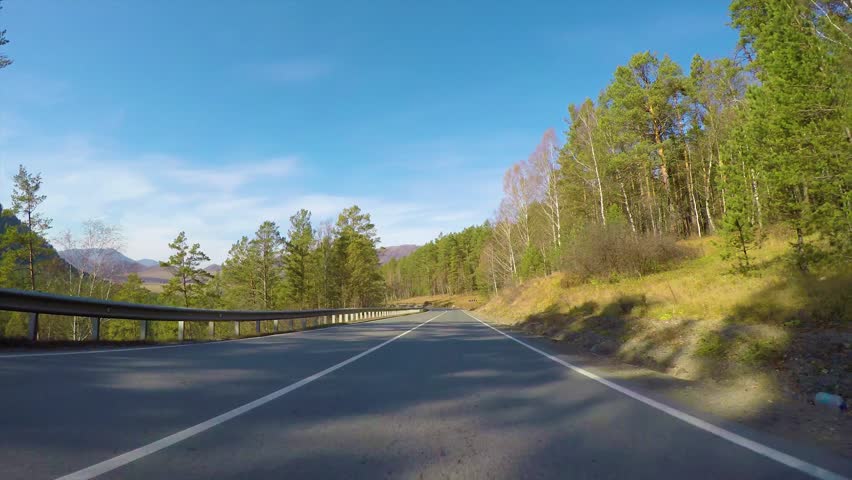 Driving down a quiet rural highway during the day in autumn. Seminsky pass, Chuysky tract, Siberia, Russia.
