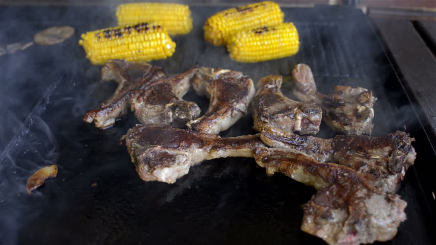 Mutton chops and corn cooking on a BBQ hot plate.