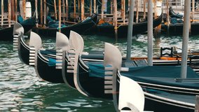 Beautiful black gondolas stand and rock on the waves of the Grand Canal in Venice