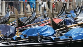 VENICE, ITALY, SEPTEMBER 7, 2017: Venetian gondolas stand on the canal in the rain, Beautiful black gondolas stand and rock on the waves