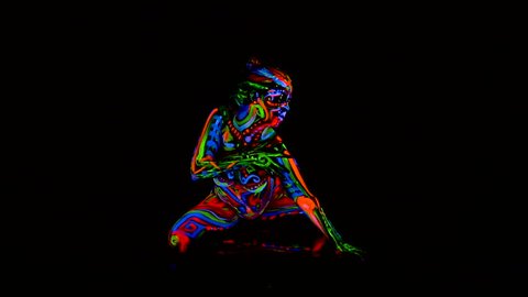 Beautiful young sexy girl in lingerie dancing with ultraviolet paint on her body. Girl with neon bodyart in color light.