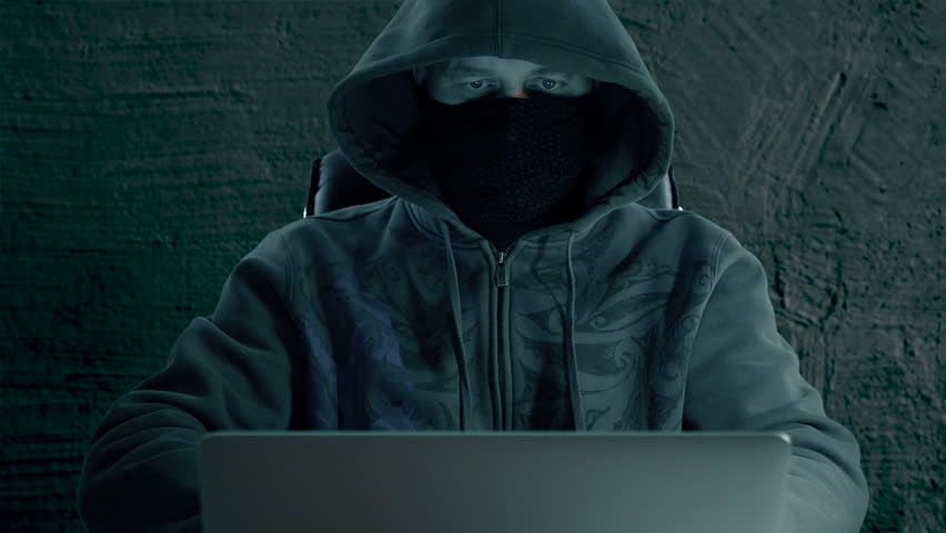 A man in hood sitting at table and coding on laptop. Dark night. Front view close up. Hacker in balaclava mask working at computer. Royalty-Free Stock Footage #33059332