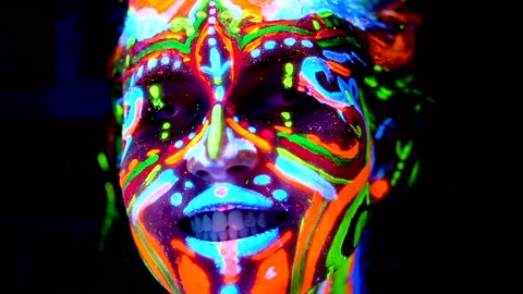 Close-up Emotions of young bodyarted avatar girl in ultraviolet light. Face of woman in color light.