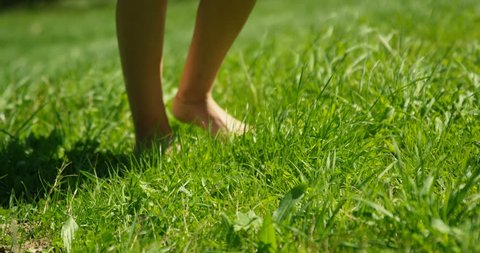 Close-up Shot of the Woman's Feet Walking on the Green Summer Grass. She Wears Stylish Dress and Holds Mobile Phone. Happy Summer Time. Shot on RED Epic 4K UHD Camera.