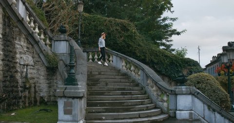Stylish Young Woman in a Hat Walks Down the Stairs in the Historic Part of the Old Town. Shot on RED Epic 4K UHD Camera.