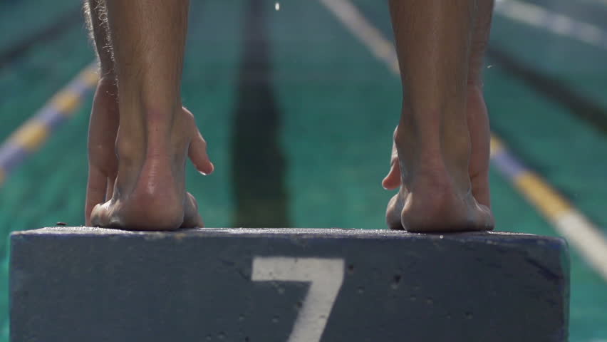 Slow-Motion Shot Of A Professional Male Swimmer Jumping Off The Starting Block