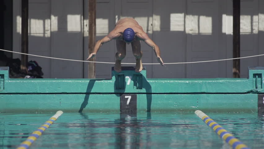 Slow Motion Shot Of A Professional Male Swimmer Jumping Off Swim Start Block