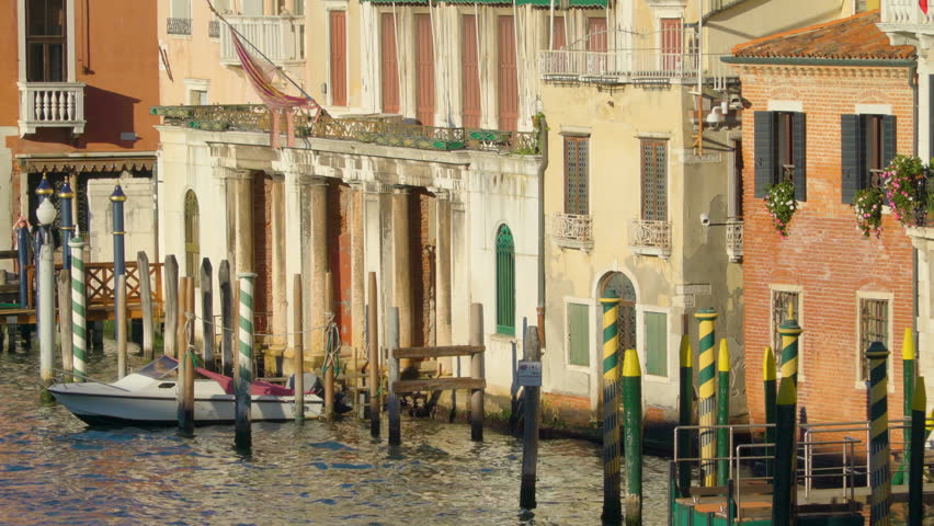 The big buildings surrounding the grand canal and some wooden poles in the city of Venice in Italy