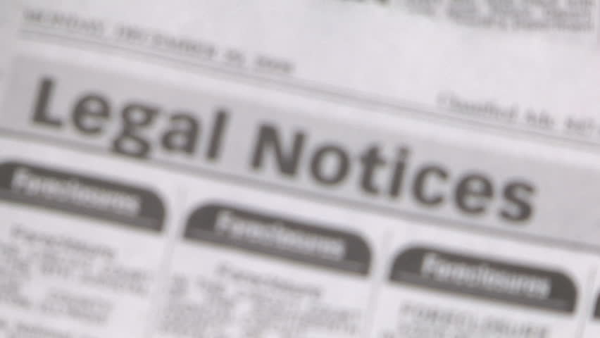magnifying glass focuses on the foreclosures section of the newspaper