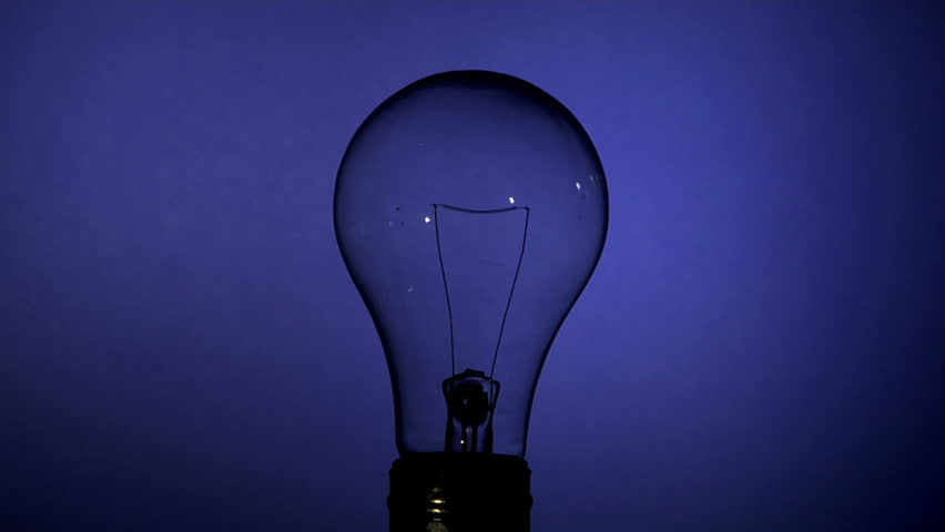 lightbulb slowly turns on against a blue wall