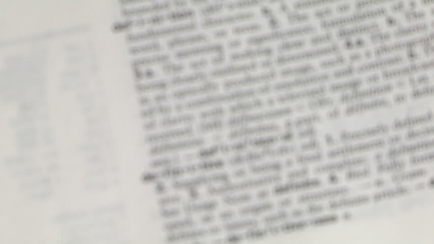 magnifying glass focuses on the word definition in a dictionary