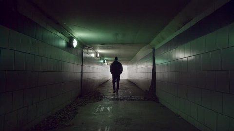 Man is walking to the end of the tunnel. Light at the end of the tunnel.