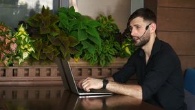 Educational consultant talking to student by laptop video call with headset microphone. Handsome serious man has beard and wears black shirt. Concept of assisting students in making decisions and