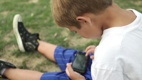 Young child playing on cell phone in grass