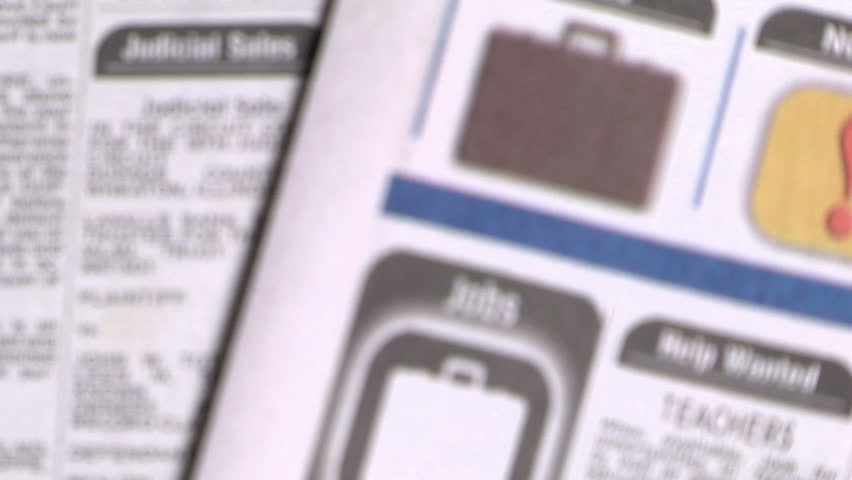 magnifying glass focuses on the jobs sections of the newspaper
