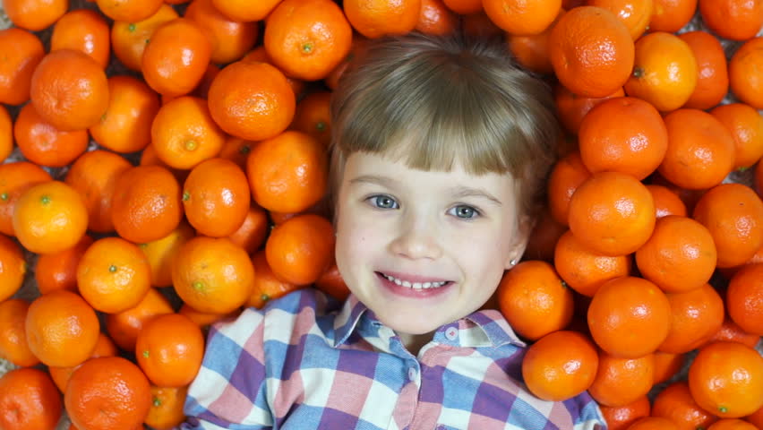 Happy child in oranges. Girl sends a kiss. Top view