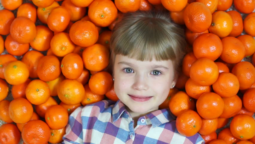 Girl lying in oranges. Looking at the camera