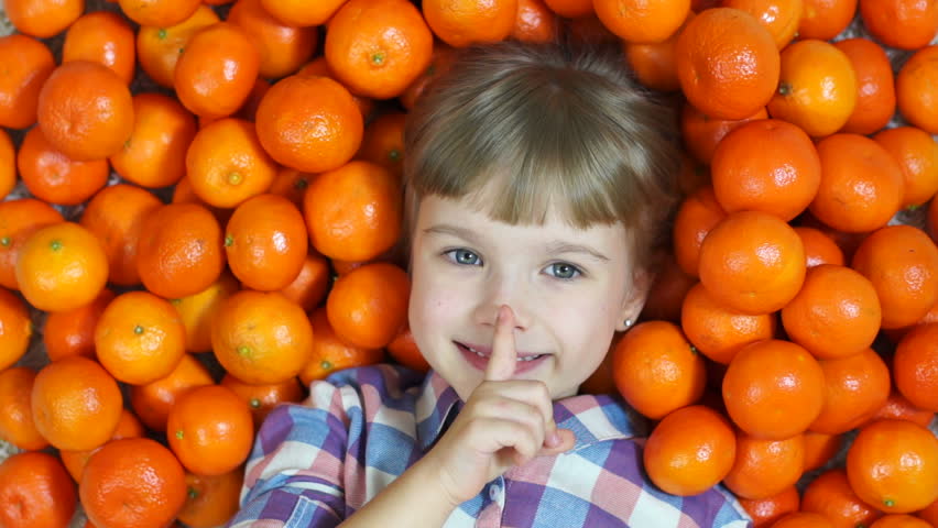 Hush hush. Happy child in oranges. Looking at camera