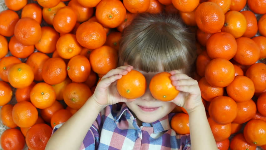 Girl orange. Happy child lying in oranges. Girl looking at camera