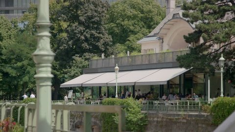 Camera pans from the beautifully path next to the Wienfluss in the Stadtpark to a famous Restaurant, called Meierei.
