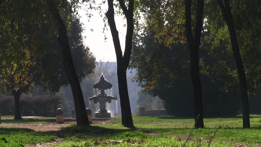 Rome, Italy. Panphili Park, passage of cyclists and joggers in the park. Fountain in background