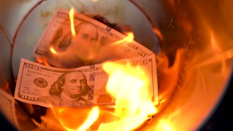 Burning dollars in the trash can close-up