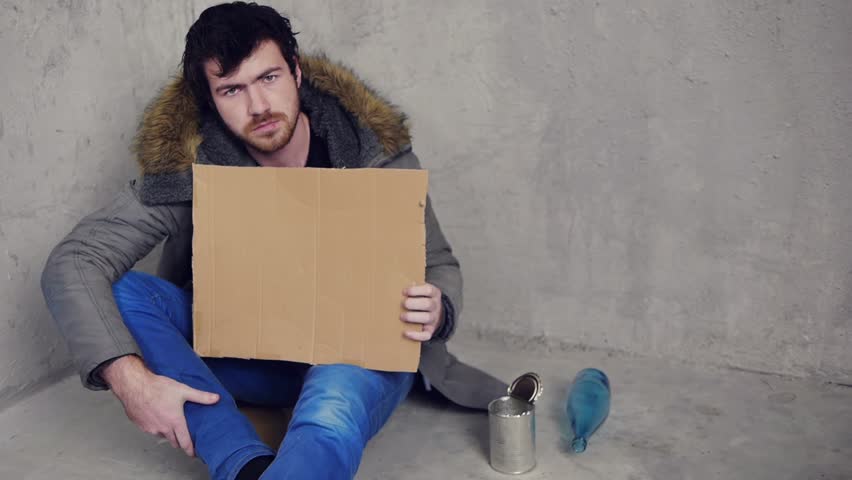 homeless man sitting on the floor with a cardboard